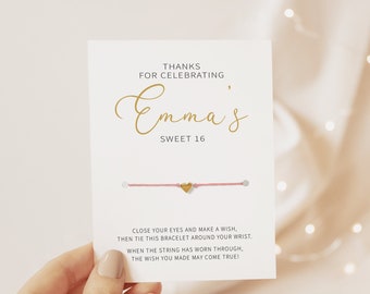 May include: A pink string bracelet with a gold heart charm and a card that says "Thanks for celebrating Emma's Sweet 16. Close your eyes and make a wish, then tie this bracelet around your wrist. When the string has worn through, the wish you made may come true!"