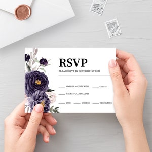 May include: A white RSVP card with black text and a floral design featuring purple and pink flowers. The text reads "RSVP, Please RSVP by October 1st 2022, Happily Accepts With, Guests, Regretfully Declines, Fish, Chicken, Vegetarian".