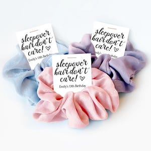 May include: Three fabric hair scrunchies in light blue, soft pink, and lavender. Each scrunchie is attached to a white card featuring the black text "sleepover hair don't care!" with a heart icon and "Emily's 13th Birthday" printed below.