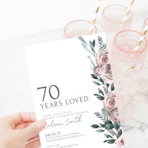 May include: A white invitation card with a floral design in shades of pink and green. The text on the card reads "70 Years Loved" and includes details for a birthday celebration honoring Selena Smith on August 24, 2021.