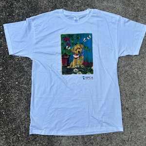 May include: White t-shirt with a graphic of a small dog sitting in a flower pot. The graphic is surrounded by flowers and butterflies. The text "SPCA" is printed below the graphic.
