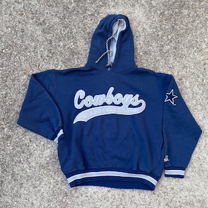 Puede incluir: Sudadera con capucha azul marino con la palabra "Cowboys" en escritura blanca en el pecho. La palabra "FOOTBALL" está debajo de la palabra "Cowboys". Una estrella blanca está en la manga derecha.