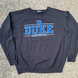 Może przedstawiać: Czarna bluza z niebiesko-białym logo Duke Blue Devils.