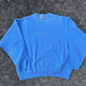 Pode incluir: Uma camisa de frio azul claro com o texto "Atlantic Dream" em branco na frente.