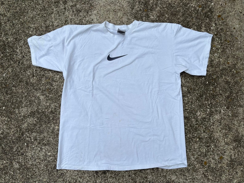 May include: White t-shirt with a black Nike swoosh logo.