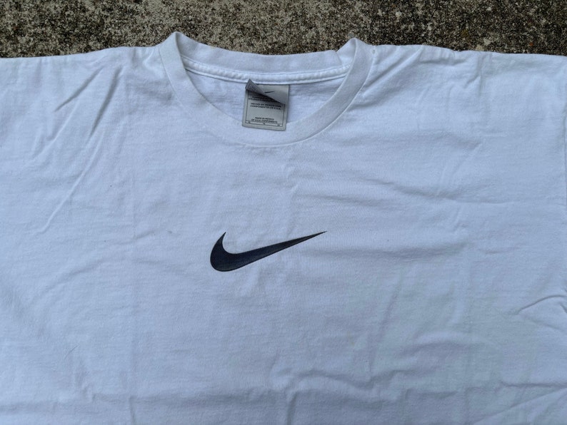 May include: White t-shirt with a black Nike swoosh logo.