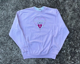 May include: A lavender sweatshirt with a pink heart graphic featuring a white cat and the text "Some is always the cat".