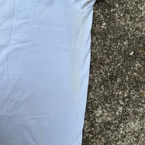 May include: A white t-shirt with a slight yellow stain on the underarm.