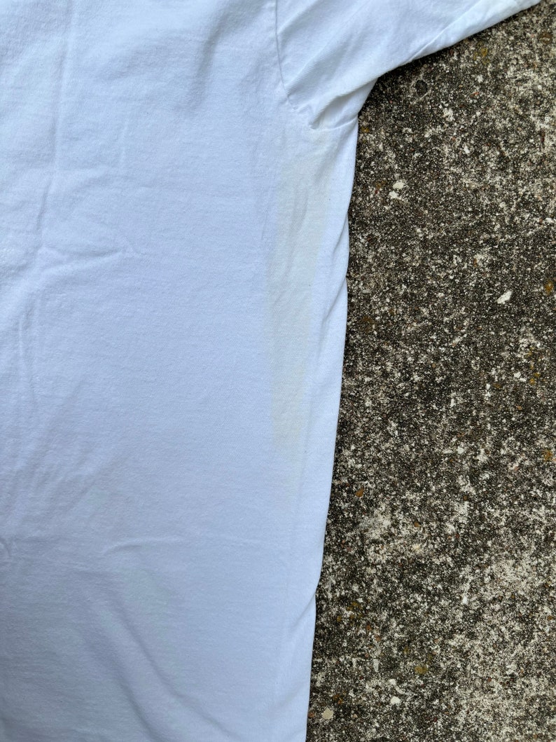 May include: A white t-shirt with a slight yellow stain on the underarm.