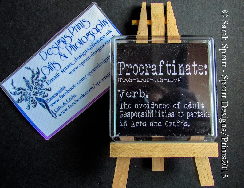 May include: A black and white definition of the word "Procraftinate" on a small wooden easel. The definition is "The avoidance of adult Responsibilities to partake in Arts and Crafts."
