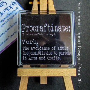 May include: A black and white definition of the word "Procraftinate" on a small easel. The definition is "The avoidance of adult Responsibilities to partake in Arts and Crafts."