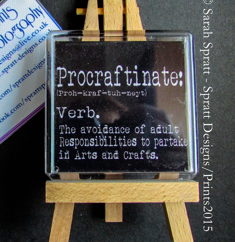 May include: A black and white definition of the word "Procraftinate" on a small easel. The definition is "The avoidance of adult Responsibilities to partake in Arts and Crafts."