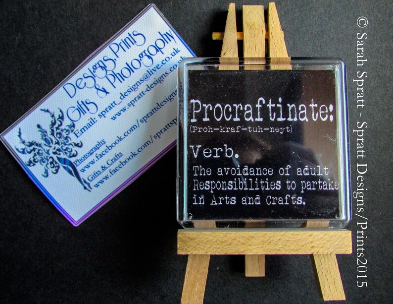May include: A black and white definition of the word "Procraftinate" on a small wooden easel. The definition is "The avoidance of adult Responsibilities to partake in Arts and Crafts."