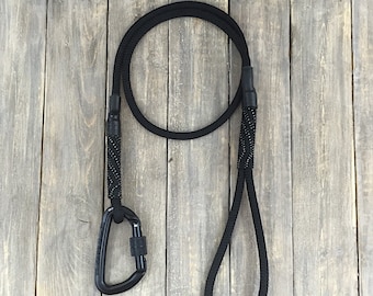 May include: Black rope dog leash with a black carabiner clip. The leash has a loop at one end for holding.