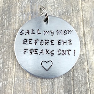 Puede incluir: Llavero de metal plateado con el texto "CALL my mom BEFORE SHE FREAKS OUT!" y un pequeño corazón.