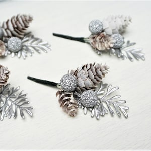 May include: Four silver and brown pine cone and berry picks with silver leaves. The picks are perfect for adding a touch of winter to your home decor.