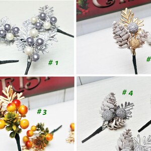 May include: Four different types of Christmas floral picks. The first pick has silver leaves with white and gray pearl-like berries. The second pick has white pine cones with gold glitter and a gold leaf. The third pick has green leaves with orange berries and gold accents. The fourth pick has white pine cones with silver glitter and a silver leaf.