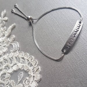 May include: Silver adjustable bracelet with a silver charm that reads "Alhamdulillah".