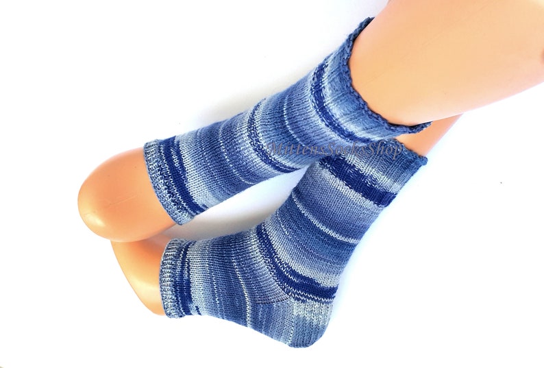 A pair of blue and white striped hand knit yoga socks with heel  with a light blue and white color gradient. The socks are made of a soft, comfortable sock yarn and are perfect for everyday wear. The socks are on a pair of mannequin feet.