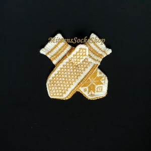 May include: A pair of white knitted mittens with a yellow geometric pattern. The mittens are folded in half and the pattern is visible on both sides.