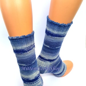 A pair of blue and white striped hand knit yoga socks with heel  with a light blue and white color gradient. The socks are made of a soft, comfortable sock yarn and are perfect for everyday wear. The socks are on a pair of mannequin feet.