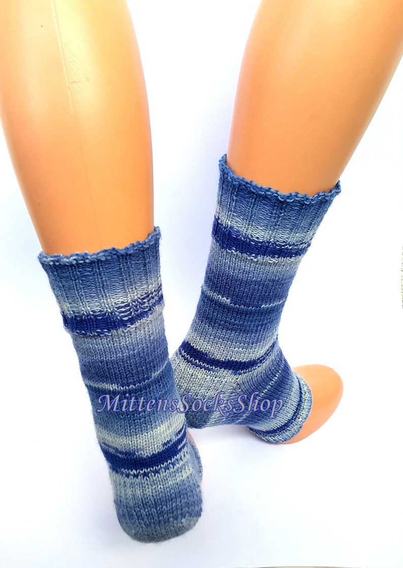A pair of blue and white striped hand knit yoga socks with heel  with a light blue and white color gradient. The socks are made of a soft, comfortable sock yarn and are perfect for everyday wear. The socks are on a pair of mannequin feet.
