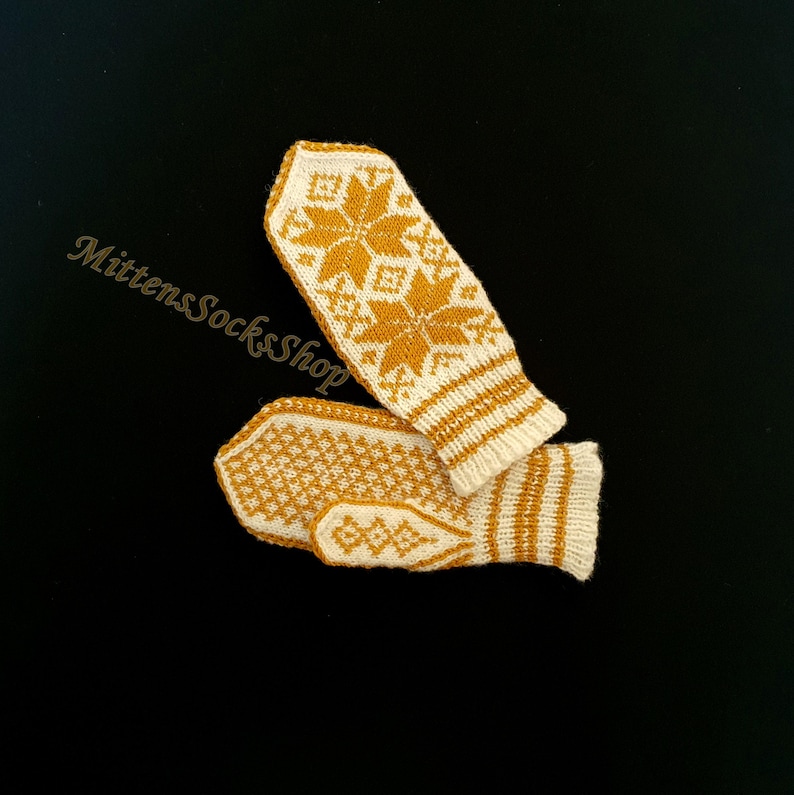 May include: A pair of knitted mittens with a white background and a yellow snowflake pattern. The mittens are folded together.