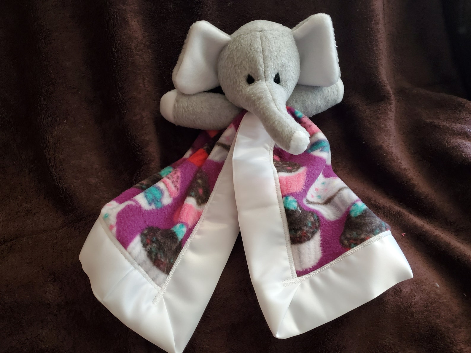 Mini Elephant Blanket Buddy Who is Oh so Cuddly With a Cupcake Design on a Purple Background and