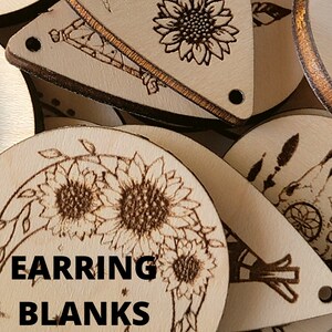 May include: A collection of unfinished wooden earring blanks with various etched designs. The designs include sunflowers, feathers, and a dreamcatcher. The text "EARRING BLANKS" is printed in black on one of the blanks. Each blank has a small hole for attaching earring hardware.