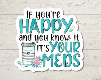 May include: A white sticker with blue and green text that reads "If you're happy and you know it, it's your meds". The sticker features a cartoon pill bottle with the label "RX" and a floral design.