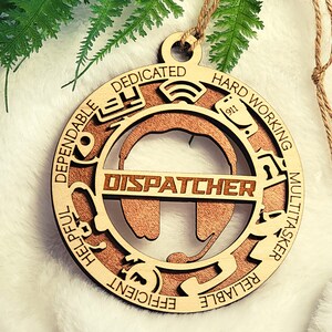 May include: Wooden Christmas ornament with the word "DISPATCHER" in the center and a circle of words around it, including "dependable", "helpful", "efficient", "reliable", "multitasker", "hard working", and "dedicated".