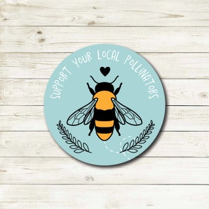 May include: A blue and white round sticker with the text "Support Your Local Pollinators" and a black and yellow bee illustration.