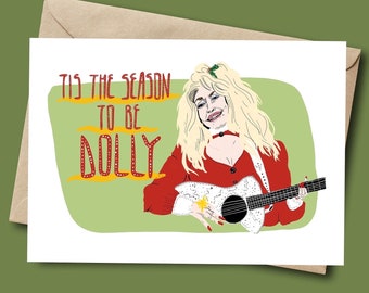 Könnte beinhalten: Grußkarte mit einer Illustration einer Frau in roter Kleidung, die Gitarre spielt. Die Karte trägt den Text "Tis the Season to be Dolly" in roter und gelber Schrift auf grünem Hintergrund. Die Karte befindet sich in einem braunen Umschlag.