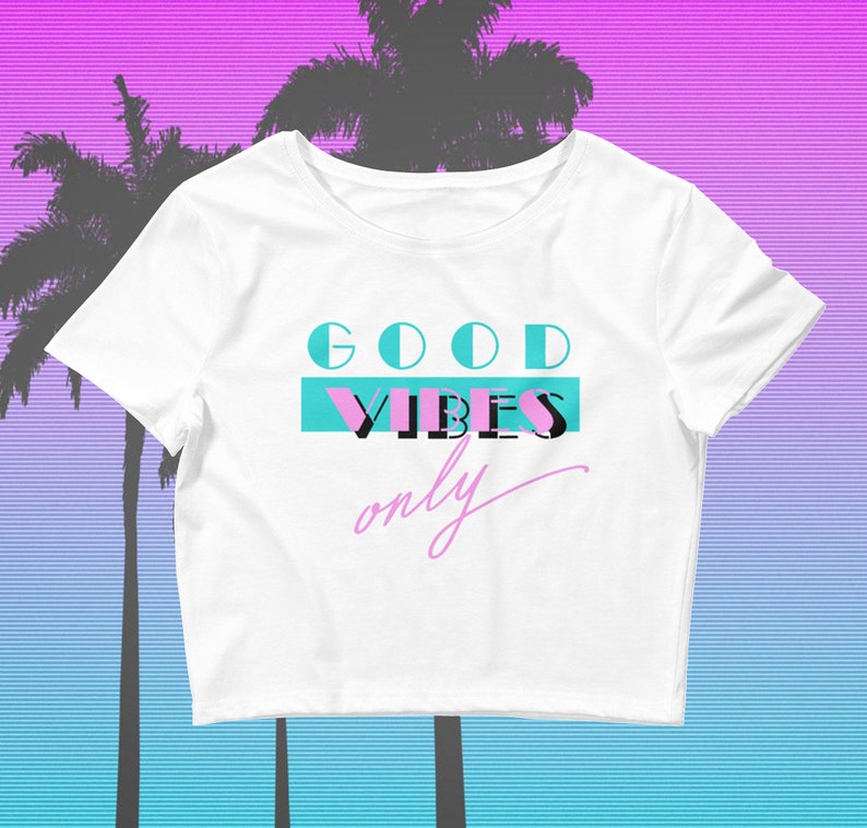 May include: White cropped t-shirt with the text "GOOD VIBES only" in blue, pink, and black lettering.