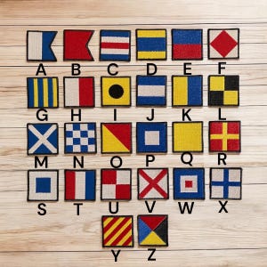 May include: A collection of 26 square patches, each displaying a different nautical flag signal. The flags are in various colors, including red, blue, yellow, and white, and are arranged in a grid with letters A through Z.
