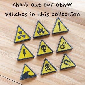 Peut inclure: Ensemble de patchs triangulaires jaunes et noirs avec divers symboles de danger, dont la radioactivit&eacute;, le feu, la foudre, une t&ecirc;te de mort, des engrenages, un cr&acirc;ne et des os crois&eacute;s, une vague, un point d'exclamation et un aimant. Le texte "check out our other patches in this collection" est visible.