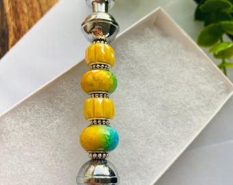 May include: A decorative letter opener with a silver handle and a colorful bead design. The beads are yellow, green, and blue, with silver accents. The letter opener is in a white box.