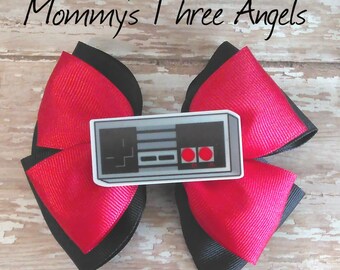 May include: A red and black bow with a white and grey Nintendo controller graphic. The graphic has red buttons and the text "Mommy's Three Angels".