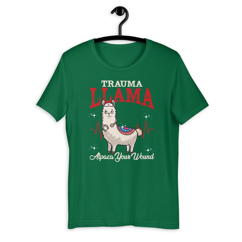 K&ouml;nnte beinhalten: Gr&uuml;nes T-Shirt mit kurzen &Auml;rmeln mit einem Cartoon-Lama, das eine Krankenschwesterm&uuml;tze und ein Stethoskop tr&auml;gt. Der Text "Trauma Llama" befindet sich &uuml;ber dem Lama und "Alpaca Your Wound" unter dem Lama.
