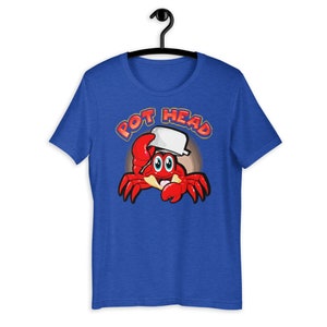 May include: A royal blue t-shirt with a cartoon crab wearing a white pot on its head. The text "POT HEAD" is written in orange and yellow above the crab.