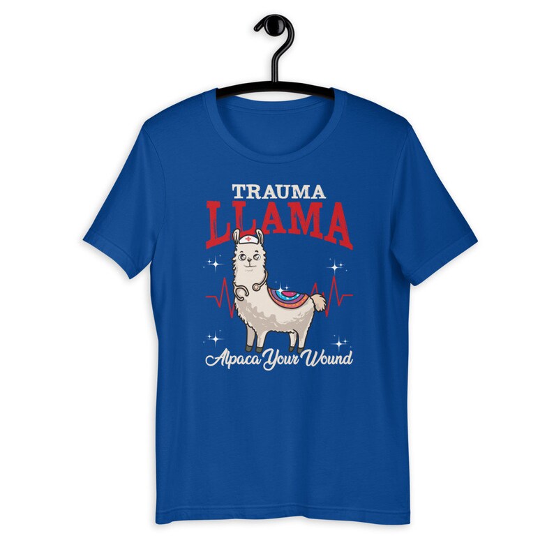 K&ouml;nnte beinhalten: Ein k&ouml;nigsblaues T-Shirt mit einem Cartoon-Lama, das eine Krankenschwesterm&uuml;tze und ein Stethoskop tr&auml;gt. Der Text "Trauma Llama" befindet sich &uuml;ber dem Lama und "Alpaca Your Wound" unter dem Lama.