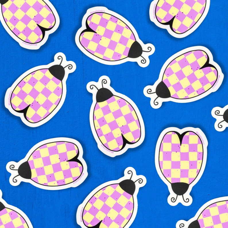 Hand drawn vinyl sticker in the shape of a beetle with a purple checkerboard pattern, cover a cobalt blue table.
