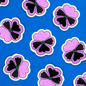 Hand drawn vinyl stickers in the shape of purple pansy flowers, cover a cobalt blue table.