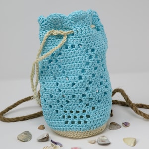 May include: A light blue crocheted drawstring bag with a beige trim and a brown rope handle. The bag is filled with seashells.
