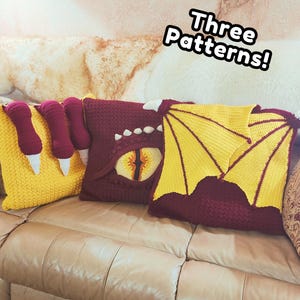 May include: Three decorative throw pillows with dragon-themed designs. One yellow pillow features a claw design, while another is burgundy with a dragon eye. The third pillow is burgundy with yellow wings. The text "Three Patterns!" is visible.
