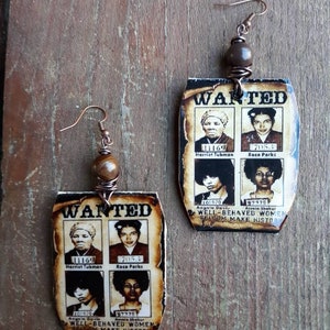 May include: Handmade earrings featuring a "Wanted" poster design with images of Harriet Tubman, Rosa Parks, Angela Davis, and Assata Shakur. The earrings have a rustic, vintage aesthetic with brown and cream tones, and are suspended from copper-colored ear wires.
