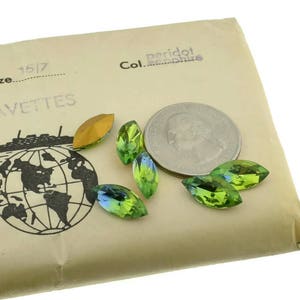 May include: A package of navette-shaped gemstones with a quarter coin for size comparison. The gemstones are peridot green and iridescent. The package has a world map graphic with a ship and the word "NAVETTES".