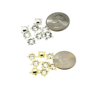 May include: Two sets of clear crystal rhinestones with silver and gold settings. The rhinestones are approximately the size of a US quarter.