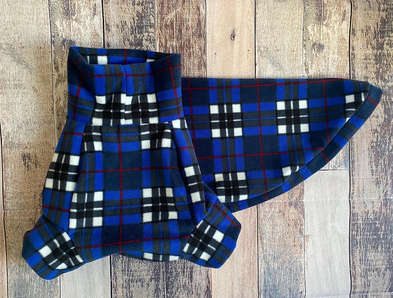 May include: A blue, black, white, and red plaid pet accessory. The item is made of a soft material and is designed to fit around a pet's neck. The plaid pattern features a repeating square design.