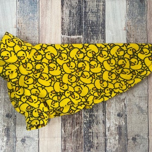 May include: A yellow fleece dog sweater with a pattern of black and yellow rubber duckies.